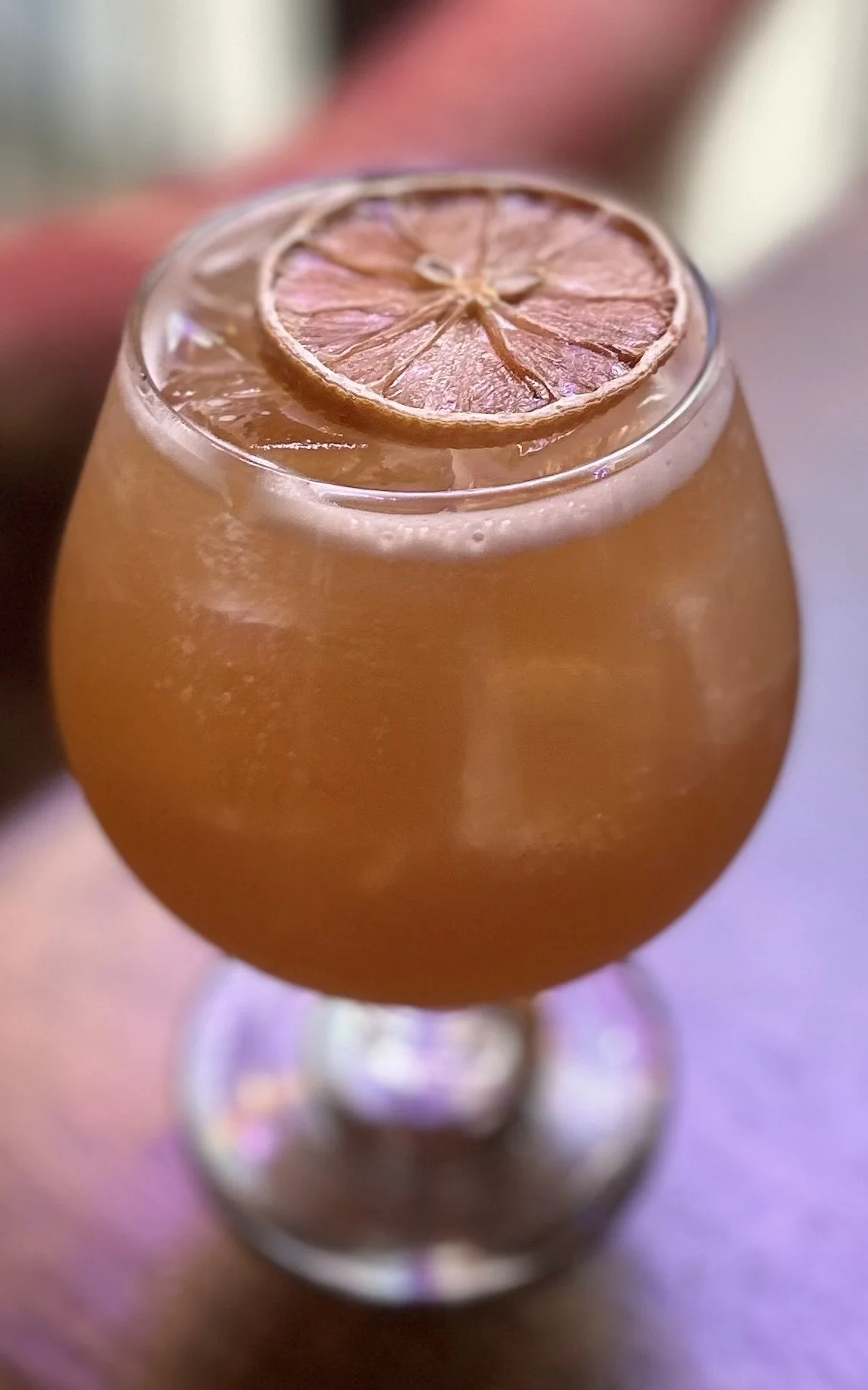 A cocktail garnished with a dried orange wheel