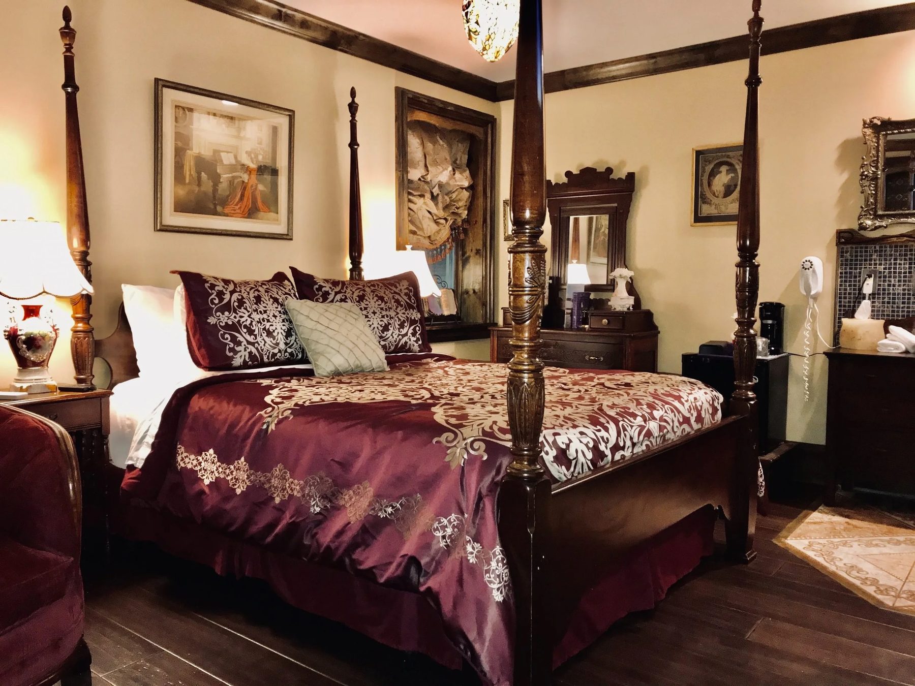 A four-poster bed dressed in burgundy silk in a Symphony Hotel guest room